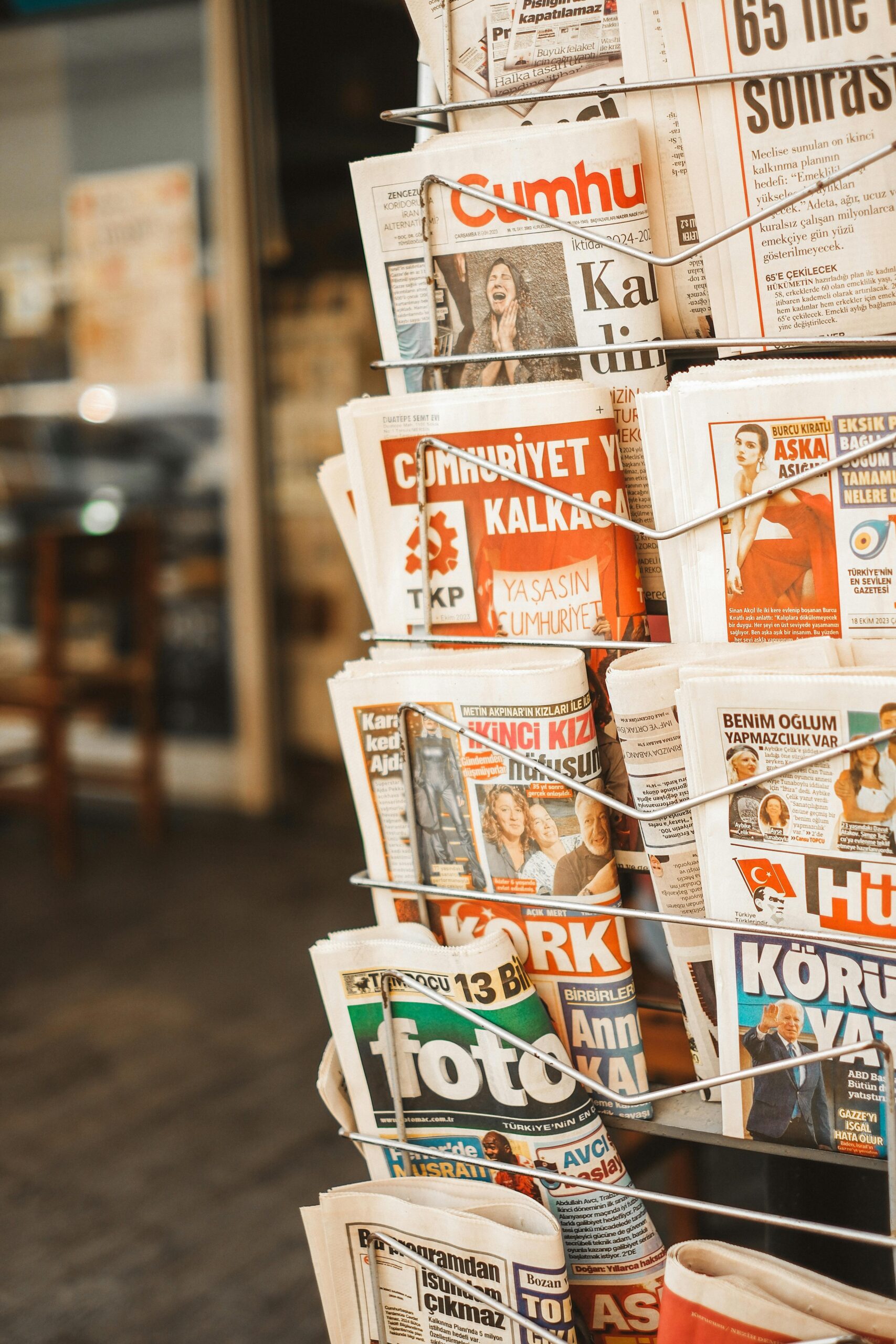 A sidewalk newspaper stand filled with various dailies and periodicals.